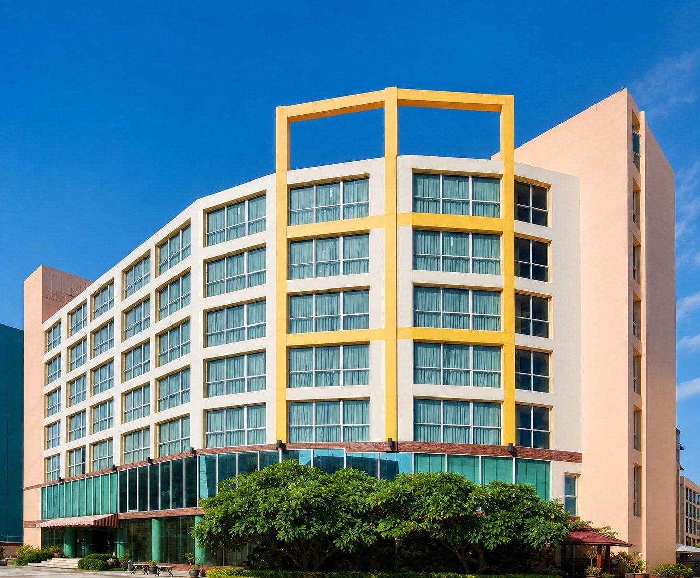 The curved facade of an Arawana hotel tower against a blue sky