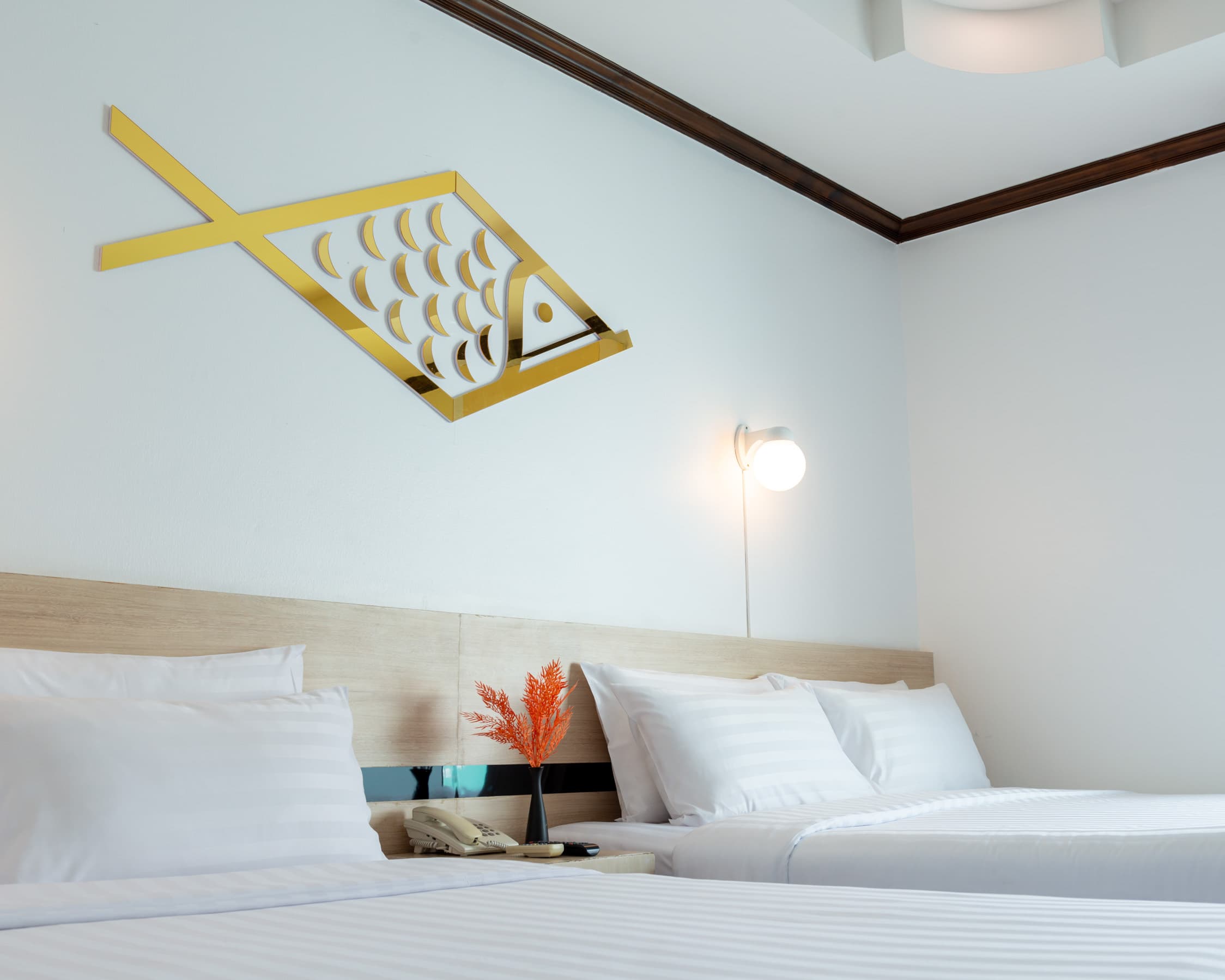 Twin beds under a gold Arawana fish emblem in a bright hotel room