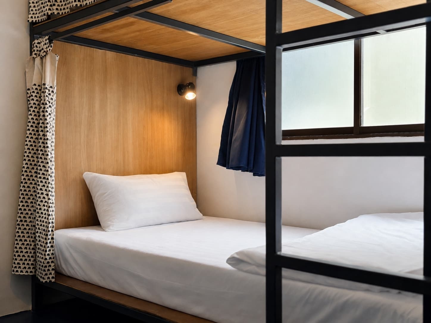 Black steel bunk beds with privacy curtains in a dorm at Arawana Hoft Hostel