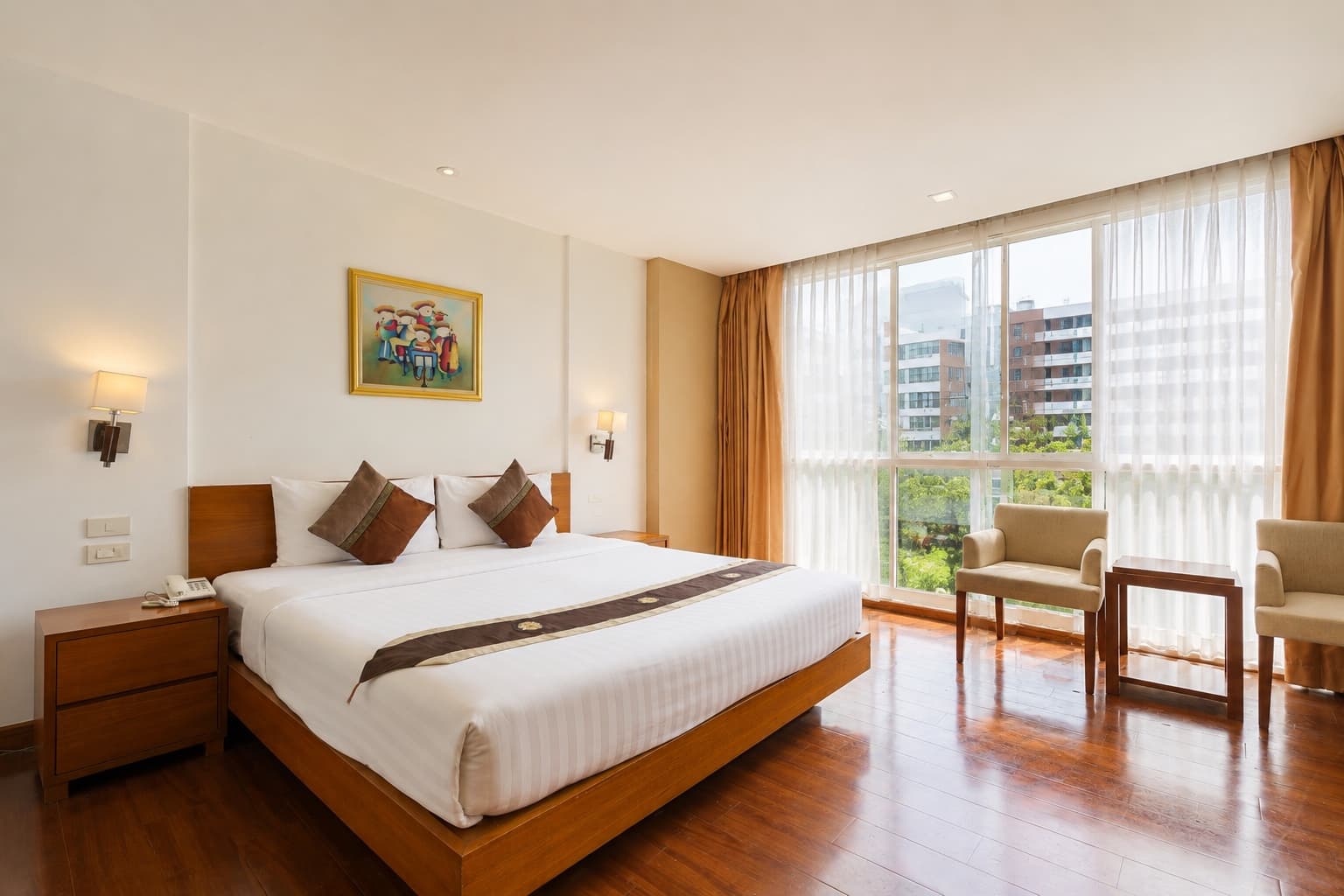 A king room with wooden floors, armchairs and a wide window at Arawana Regency Ratchada