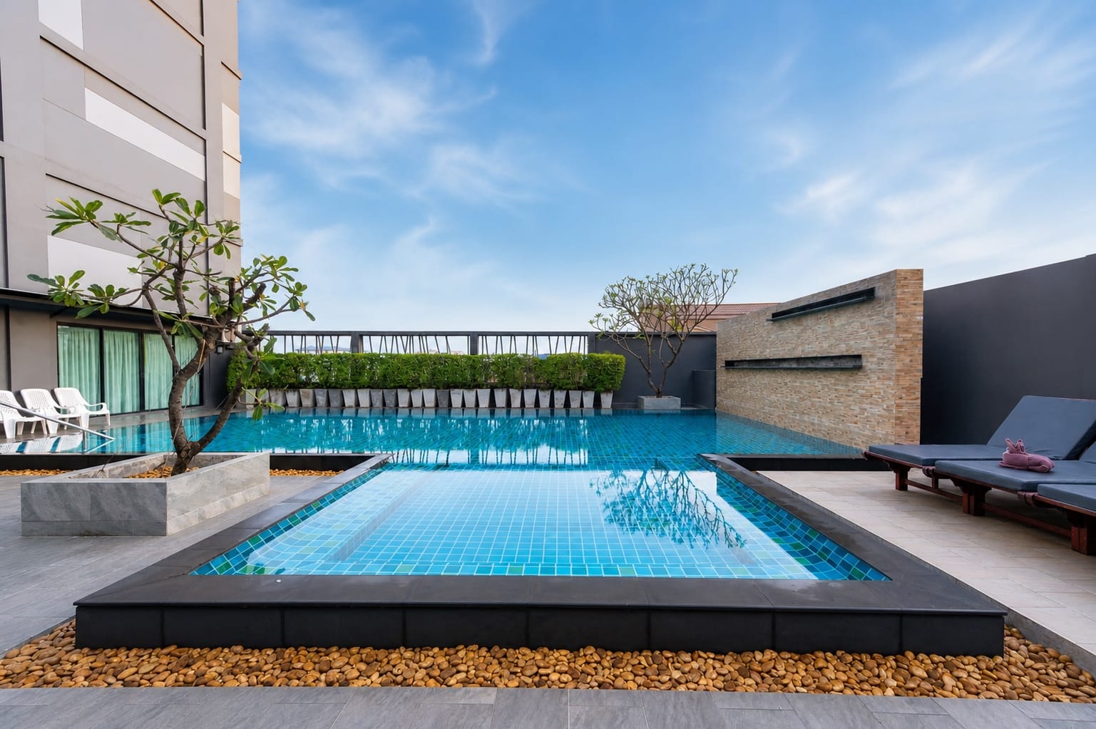 A rooftop pool with sun loungers and frangipani trees at an Arawana property