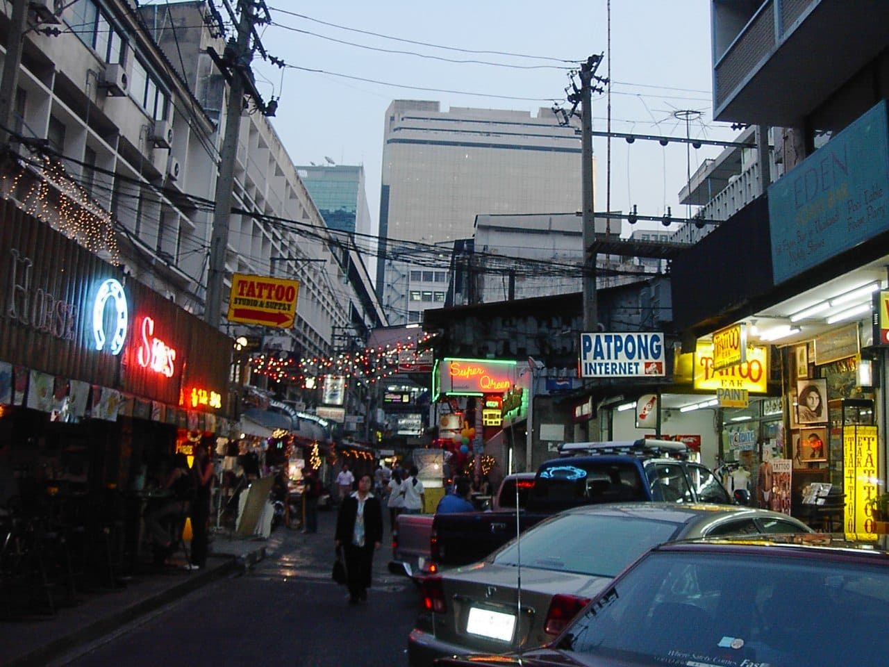 シーロム通り近く、夕暮れの Patpong に並ぶバーやタトゥー店のネオン看板