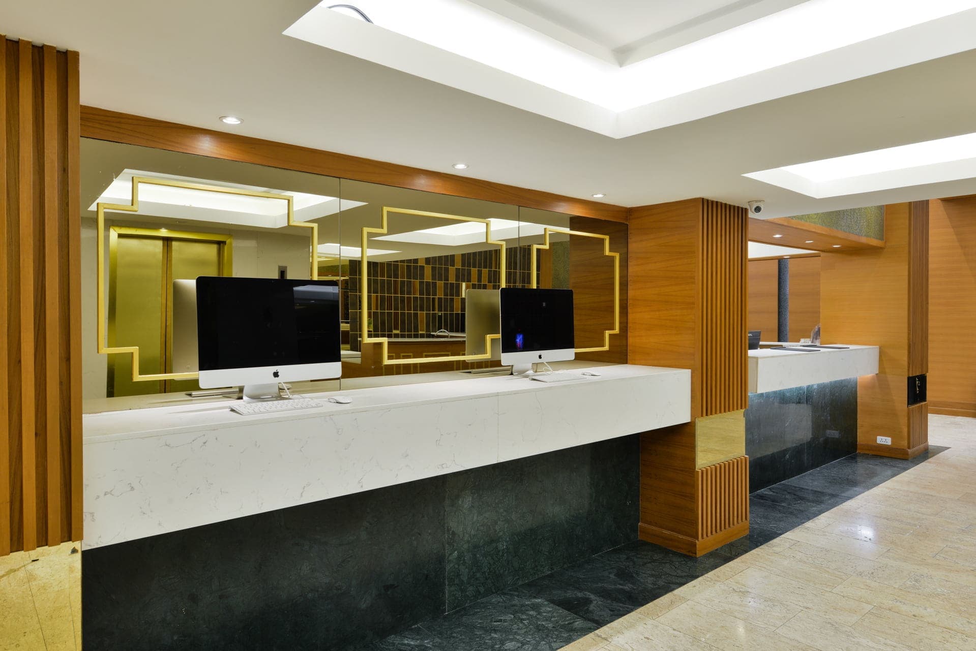 Arawana Regency Park Sukhumvit का संगमरमर का रिसेप्शन काउंटर, मेहमानों के लिए कंप्यूटर और सुनहरे फ़्रेम वाले शीशों के साथ