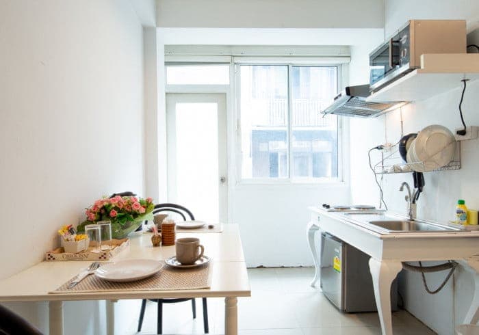 In-room kitchen and dining area with fresh flowers and place settings at Arawana Regency Park Sukhumvit.