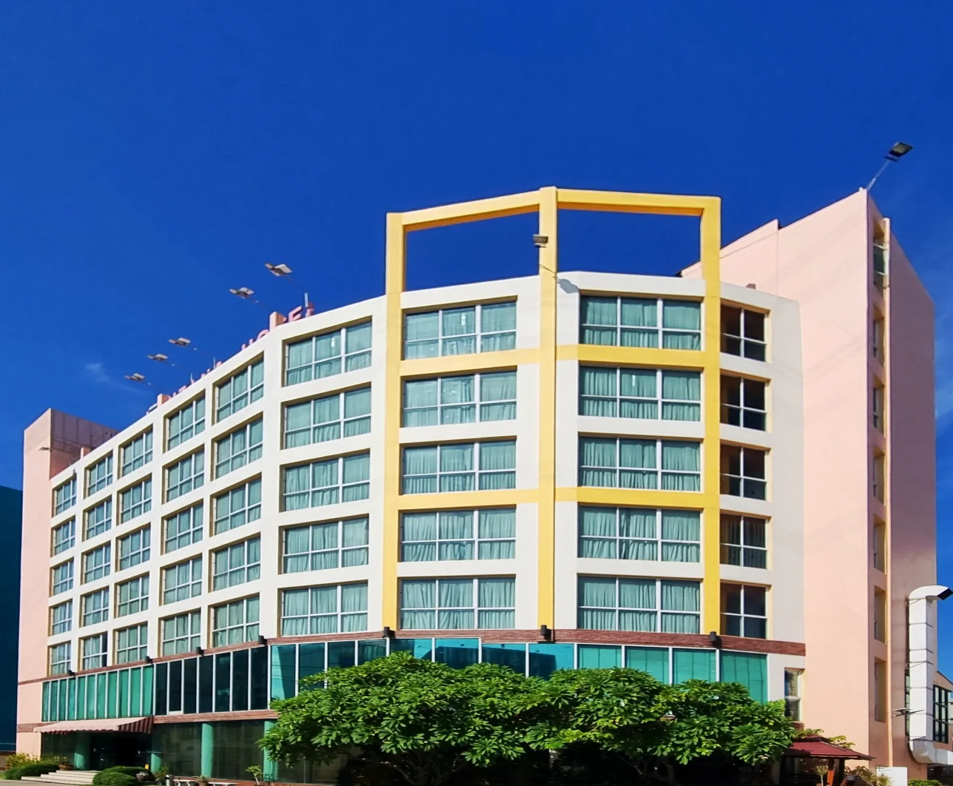 The curved yellow and white facade of Arawana Regency Ratchada against a clear blue sky