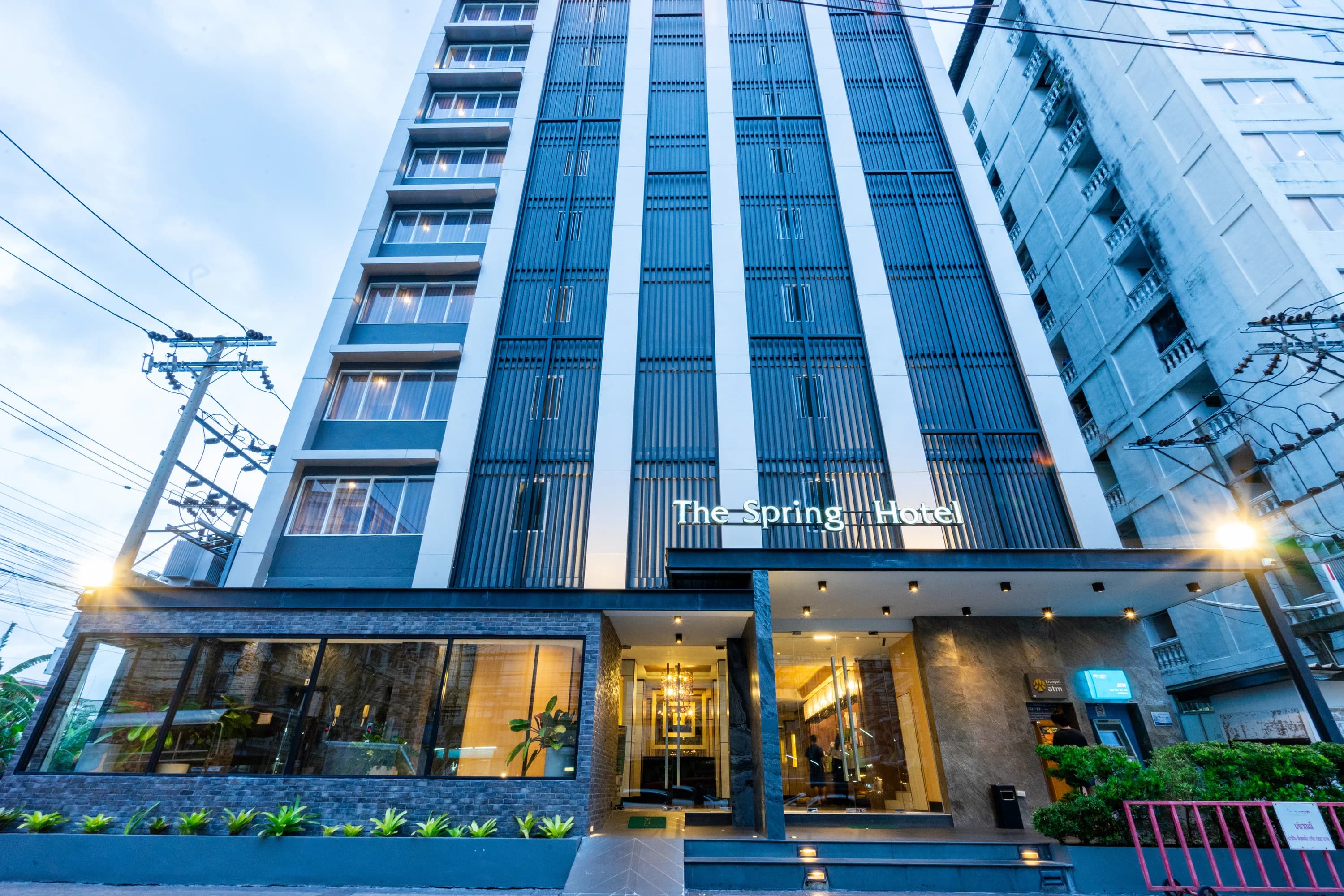 The glass tower of Arawana Regency Srinakarin at dusk, with the lobby lit at street level