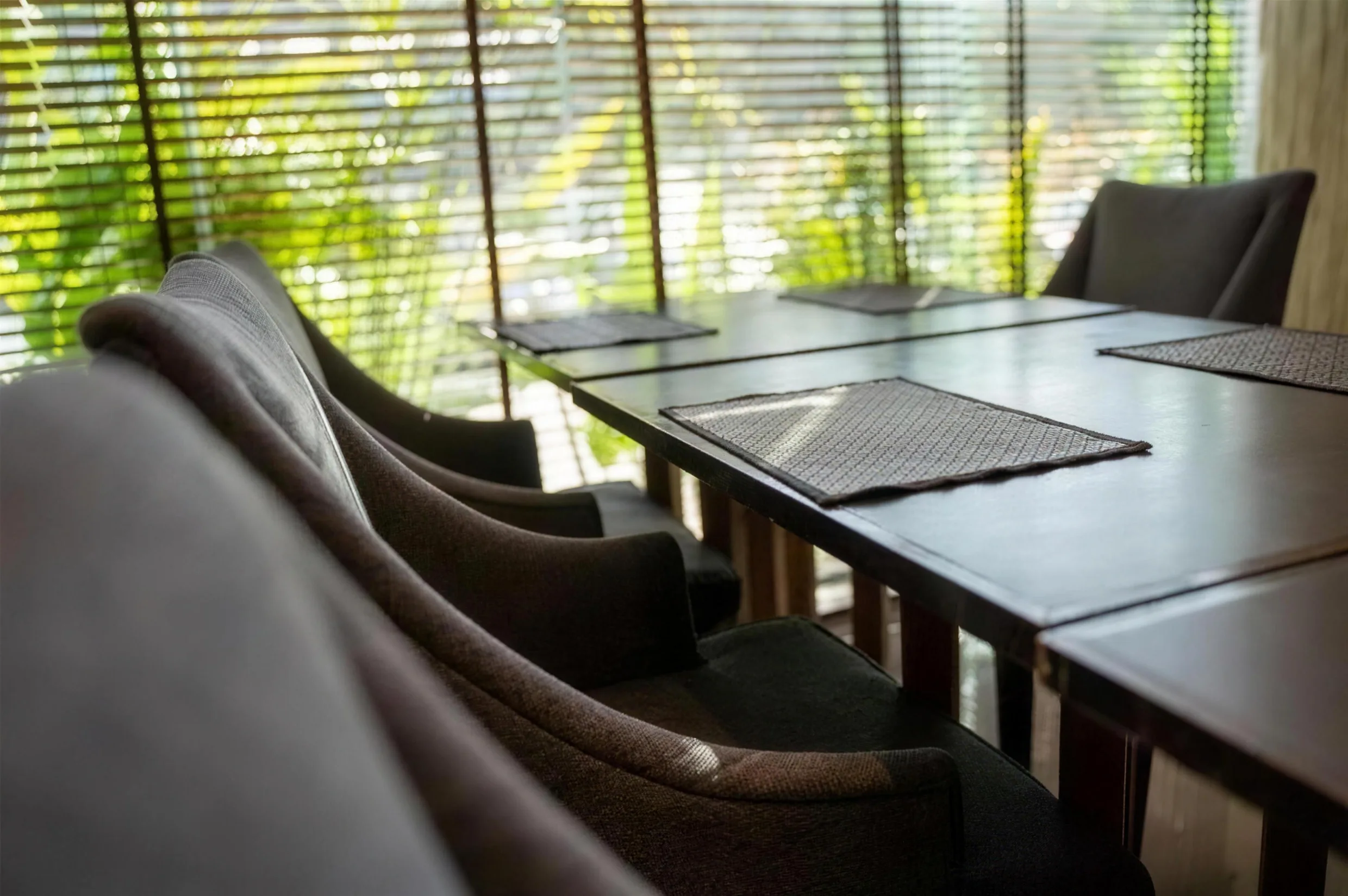 Long boardroom table with leather chairs beside a green window wall at Arawana Regency Ratchada